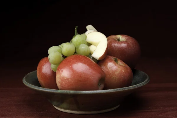 Schaal met hele en gesneden fruit. — Stockfoto