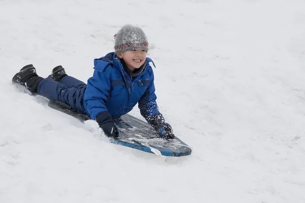 Boy slides on the snow hill. Stock Image