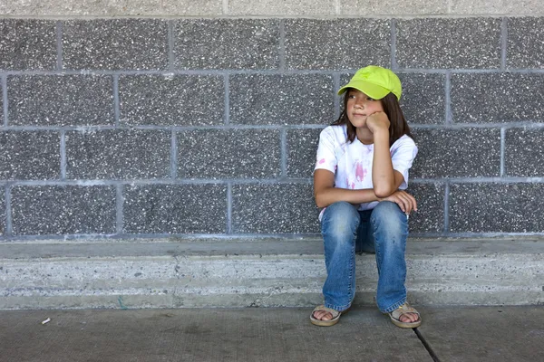 Dziewczyna siedzi przez ścianę. — Zdjęcie stockowe