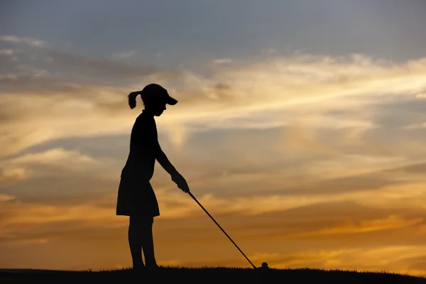 Silhouetted girl tees up. — Stock Photo, Image