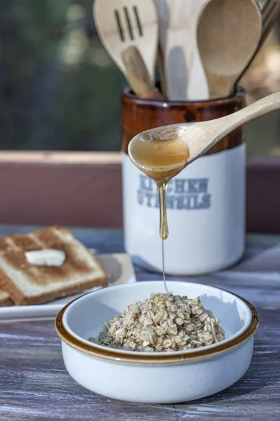 Miel vertida sobre cereal caliente . — Foto de Stock