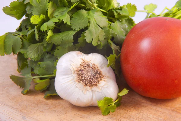 Koriander, knoflook, en een tomaat. — Stockfoto