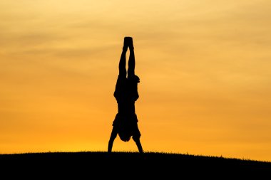 Doing a hand stand at sunset. clipart