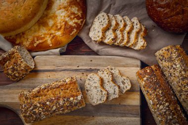 Çeşitli ekmek türleriyle çevrili bir kesme tahtasındaki ekmeğin genel görünümü.