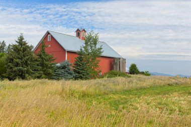 A bright red barn stands by a field in north Idaho.