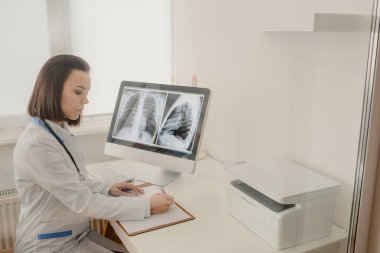 Genç kadın radyoloji doktoru röntgen ve bilgisayar tomografisi analizi ve not defterine tıbbi tanımlama.