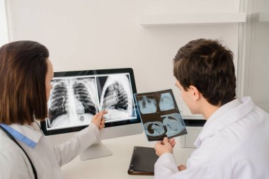 Genç doktorların geçmişe bakış radyologları röntgen ve bilgisayar tomografisi filmlerini analiz eder ve defterde tıbbi bir açıklama yapar.