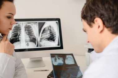 Genç doktorların geçmişe bakış radyologları röntgen ve bilgisayar tomografisi filmlerini analiz eder ve defterde tıbbi bir açıklama yapar.