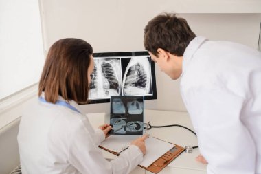 Genç doktorların geçmişe bakış radyologları röntgen ve bilgisayar tomografisi filmlerini analiz eder ve defterde tıbbi bir açıklama yapar.