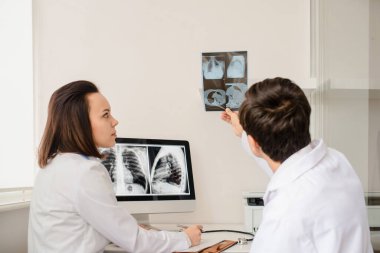 Genç doktorların geçmişe bakış radyologları röntgen ve bilgisayar tomografisi filmlerini analiz eder ve defterde tıbbi bir açıklama yapar.