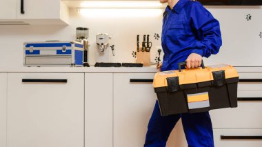 Mutfakta alet çantası tutan tesisatçı adam iş için hazırlanıyor.