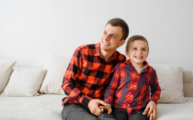 Gülen baba ve oğlu, aynı ekose gömleklerle oynuyorlar ve eğleniyorlar. Mutlu aile kavramı