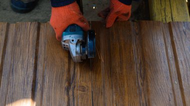 Çalışma sürecini kapatan koruyucu eldivenli işçiler elektrikli açılı öğütücüyle metal bir çatı levhası kesiyorlar. Çatı konsepti