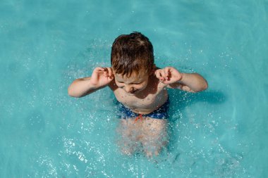 Havuzda oynayan ve gözlerini kapatan bir çocuğun en iyi görüntüsü.