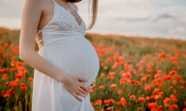 Beyaz Elbiseli Hamile Bir Kadını Elleri Karnını Kırmızı Gelincik Çiçek — Stok fotoğraf