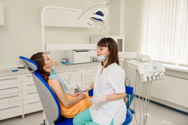 Dişçi kliniği konseptinde. Dişçi ve hasta dişçilikte birbirlerine bakıyorlar.