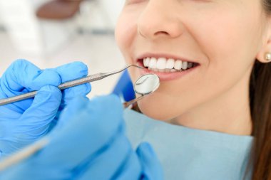 Diş aletleriyle dişçi ellerini kapatın. Hastanın dişlerini muayene edin.