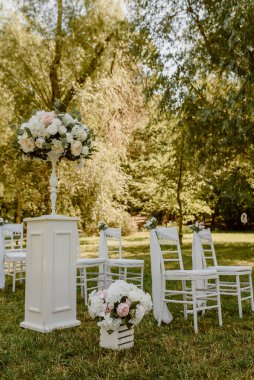 Parkta düğün seremonisi. Güllerle süslenmiş beyaz sandalyeler. Kimse yok.