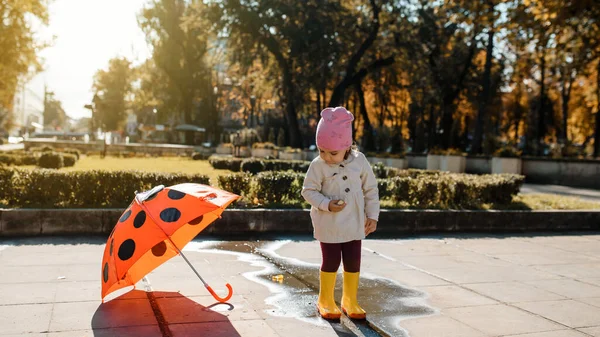 Счастливая Улыбчивая Двухлетняя Девочка Желтых Дождевых Сапогах Играет Красной Пуговицей — стоковое фото