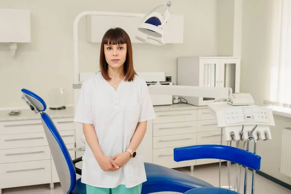 Mujer Joven Dentista Médico Medio Clínica Médica Mirando Cámara —  Fotos de Stock