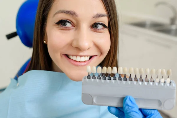 歯医者は歯科クリニックでインプラント手術を受けた患者の歯の色図で色を確認しています — ストック写真