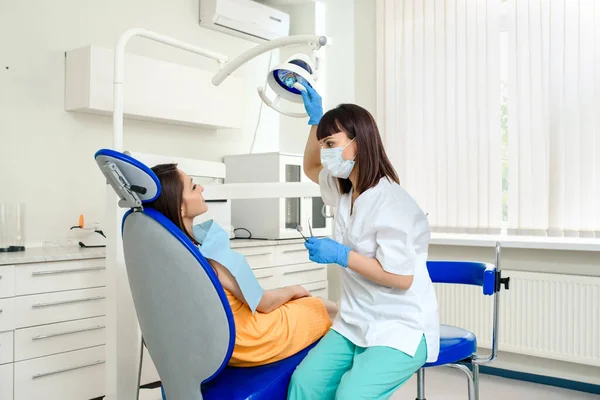 Jonge Vrouw Tandarts Met Masker Het Aanpassen Van Het Licht — Stockfoto