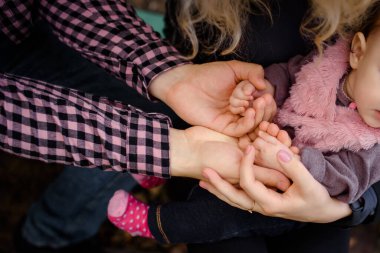 Anne ve babanın 6 aylık bebek ellerini tutarak yakın çekim. Mutlu aile kavramı