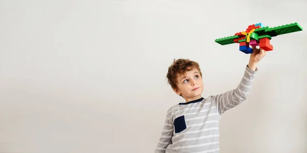 Mały Chłopiec Bawi Się Zabawkowym Samolotem Zbudowanym Plastikowych Cegieł Białym — Zdjęcie stockowe
