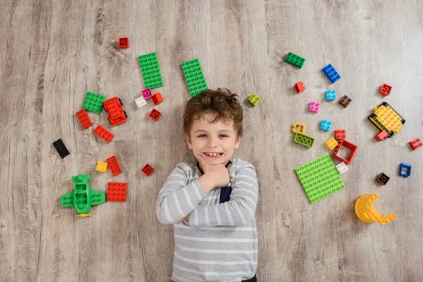 Feliz Niño Está Sonriendo Acostado Cerca Montón Ladrillos Plástico Suelo —  Fotos de Stock