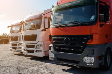 Kamyon parkında gün batımında kalan kamyonların ön görüntüsü. Nakliye konsepti. Lojistik şirketi