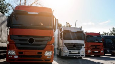 Kamyon parkında gün batımında kalan kamyonların ön görüntüsü. Nakliye konsepti. Lojistik şirketi