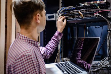 Sunucu odasında bir teknisyen / Bir mühendis / internet ağ kablosunu bağlayan ve dizüstü bilgisayarı ayarlayan