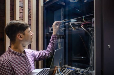 Sunucu odasında bir teknisyen / Bir mühendis / internet ağ kablosunu bağlayan ve dizüstü bilgisayarı ayarlayan