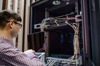 Sunucu odasında bir teknisyen / Gözlüklü bir mühendis / mühendis defteri tutar ve sunucu hatasını düzeltmek için internet bağlantısını ayarlar.