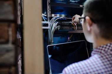 Sunucu odasında bir teknisyen / Bir mühendis / internet ağ kablosunu bağlayan ve dizüstü bilgisayarı ayarlayan