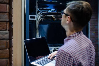 Sunucu odasında bir teknisyen / Gözlüklü bir mühendis / mühendis defteri tutar ve sunucu hatasını düzeltmek için internet bağlantısını ayarlar.
