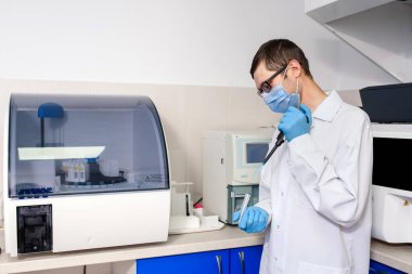 Hastane laboratuvarlarında çalışan genç bir doktor bilim adamı immünolojik kan testleri için mikropipet test tüpleri kullanıyor..
