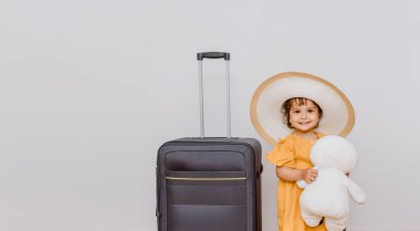 Büyük bir bavulun yanında beyaz şapkalı küçük bir kız pelüş kardan adam oyuncağıyla oynuyor. Çocuklar bir tatil konsepti istiyor. Beyaz arkaplan