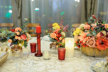 Bir sonbahar çiçeği masası süslemeleri bir balkabağında, mumlarla.