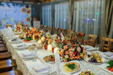 Çiçek süslemesi ve farklı yemek çeşitleri olan bir restorandaki bir masanın fotoğrafını çek..