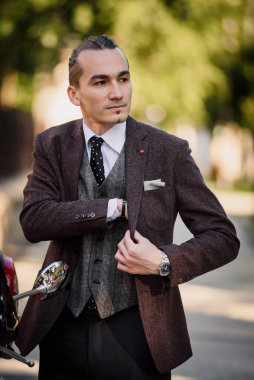 Zarif takım elbiseli genç adam sokaklarda yürüyor.