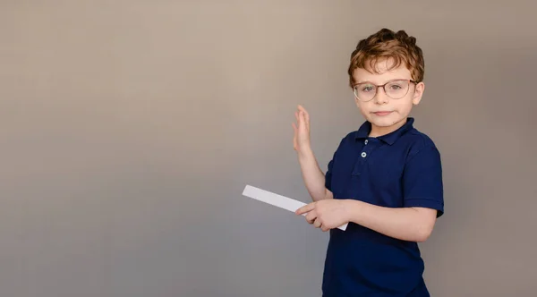 Šťastný Chlapeček Modrém Tričku Brýlích Šedém Pozadí Ukazuje Pravítkem Volné — Stock fotografie