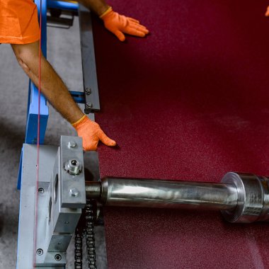 İşçilerin ellerini metal bir levha ile kapatın ve metal kiremit çatı makinesinin profil çıkarma işlemine hazırlayın. Endüstri konsepti. Üst görünüm
