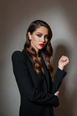 Mükemmel ciltli, güzel, koyu gri arka planda siyah ceketli, genç ve seksi bir kadının portresi.