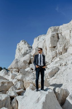 Klasik kıyafetler, ceket, kravat ve gözlüklü genç adam dağda poz veriyor.. 