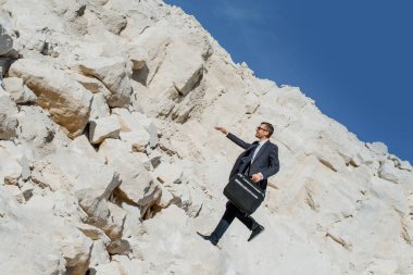 Evrak çantası ve ceketi olan genç bir işadamı dağdan düşer.. 