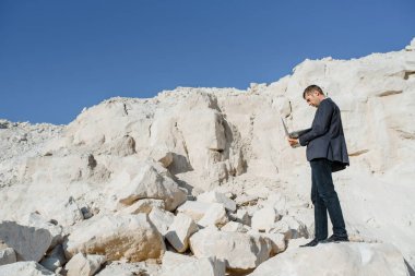 Genç iş adamı dağlarda bir bilgisayar defteri üzerinde çalışıyor. Bağımsız konsept, her yerden çalışma