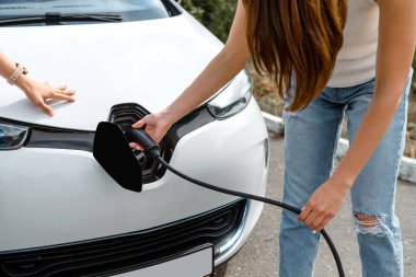 Güç kablosu tutan ellerini kapat ve elektrikli arabanın aküsünü şarj et. Çevre dostu araba, şarj istasyonunda elektrikli araba aküsü şarj ediliyor. Çevre taşımacılığı kavramı