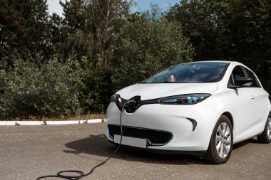 Ormanda elektrik kablosu takılı elektrikli bir araba.