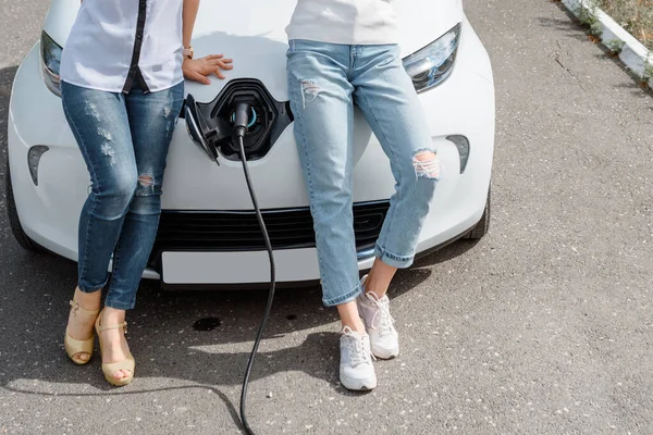 Güç kablosu tutan ellerini kapat ve elektrikli arabanın aküsünü şarj et. Çevre dostu araba, şarj istasyonunda elektrikli araba aküsü şarj ediliyor. Çevre taşımacılığı kavramı